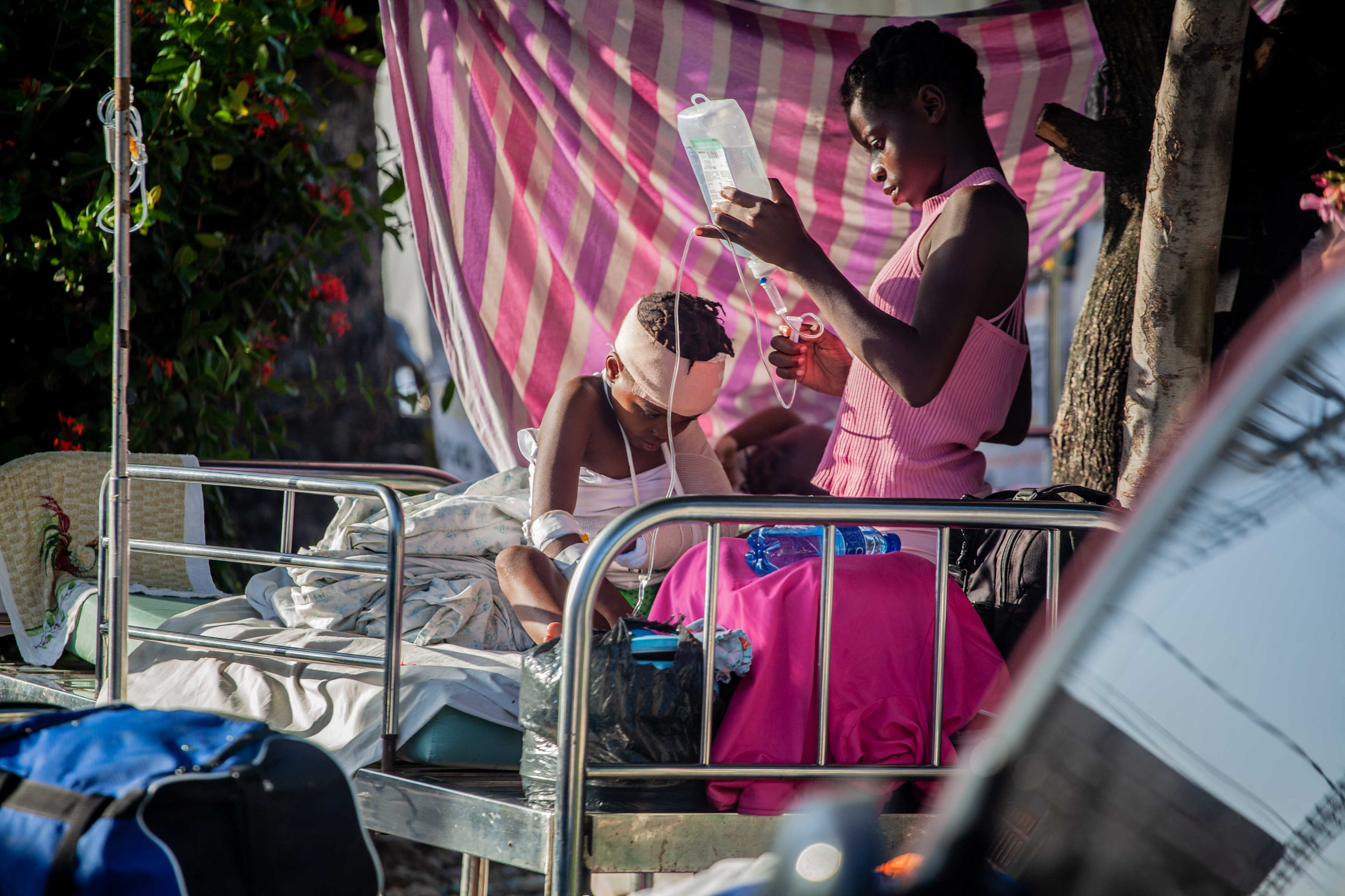 Een jongen krijgt verzorging buiten het Les Cayes General Hospital in Les Cayes, Haïti. Reddingswerkers blijven intussen zoeken naar overlevenden tussen het puin.