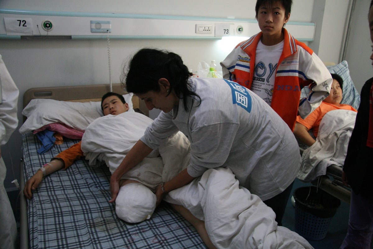 Graziella Lippolis, Rehabilitation Manager bij HI, aan het ziekenbed van een slachtoffer van de aardbeving in Sichuan. 