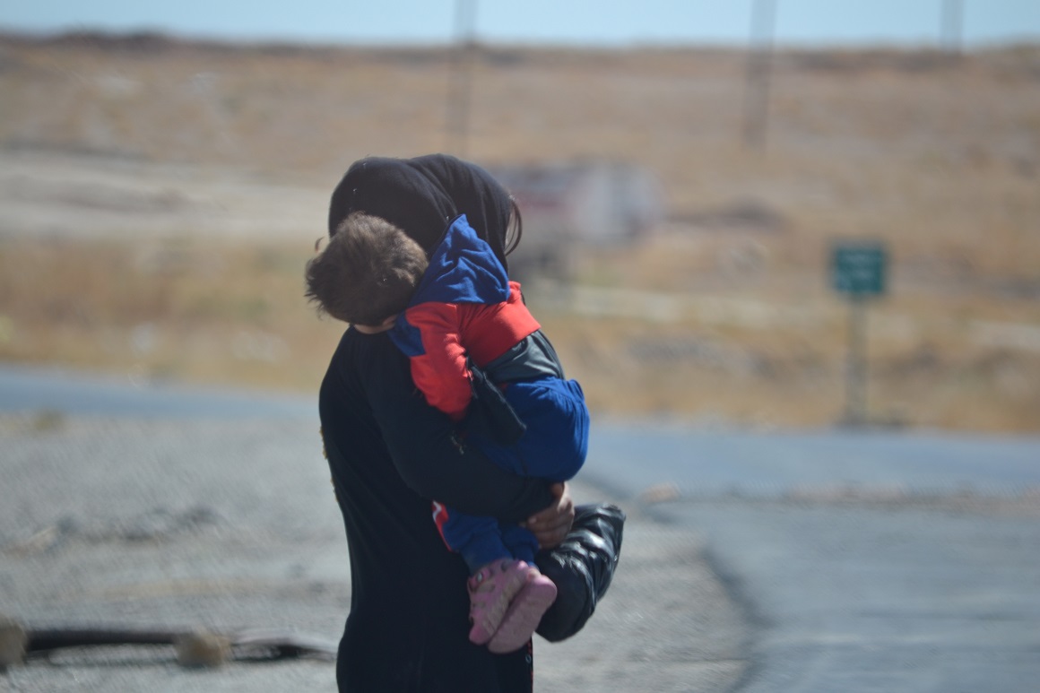 Een Syriaanse vrouw met een jongen van 2 in haar armen