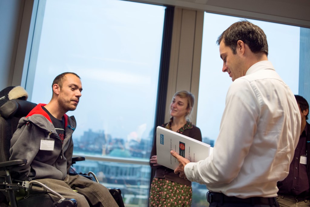 Remko kijkt toe terwijl minister Alexander De Croo de petitie van Handicap International inkijkt.