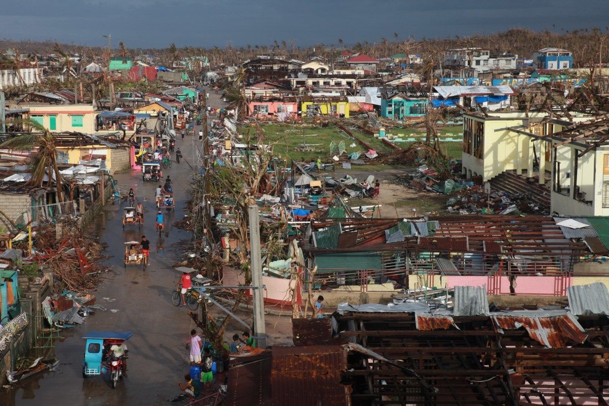 Beeld op de stad Guian na Haiyan van bovenaf: gebouwen met afgerukte daken, puin op straat, weggeblazen palmbomen