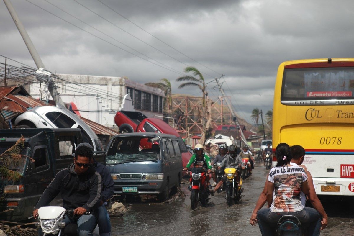 Auto's, bomen en ander vernield materiaal in een straat in Tacloban na de doortocht van tyfoon Haiyan