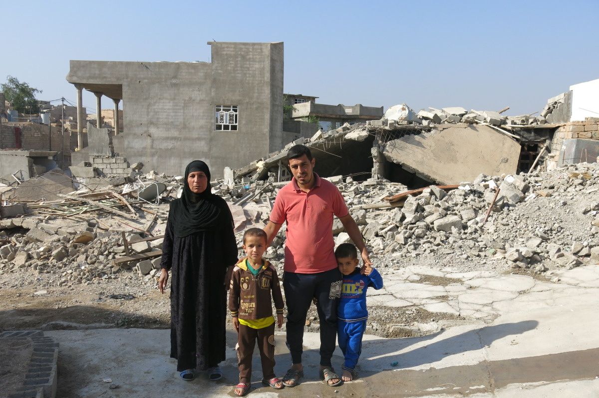 Mama, papa en twee kindjes poseren voor het puin van gebombardeerde huizen in Irak.