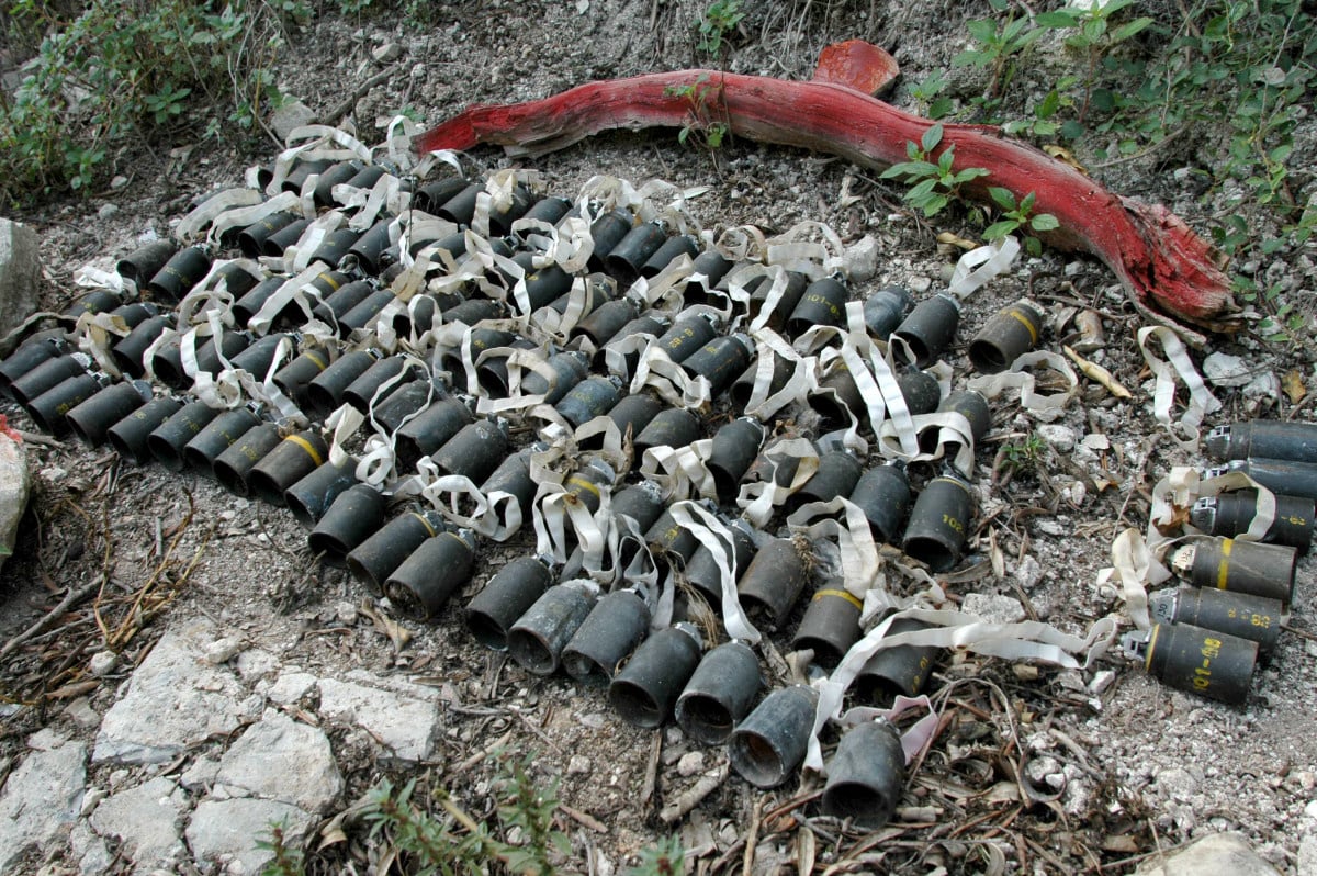 Meer dan honderd stukken clustermunitie op de grond afgebakend met een roodgeschilderde houten tak