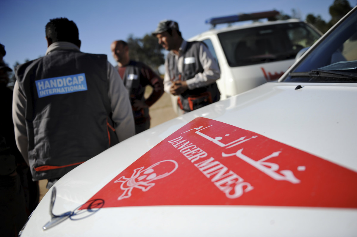 Een medewerker van Handicap International en een auto waar danger mines op staat