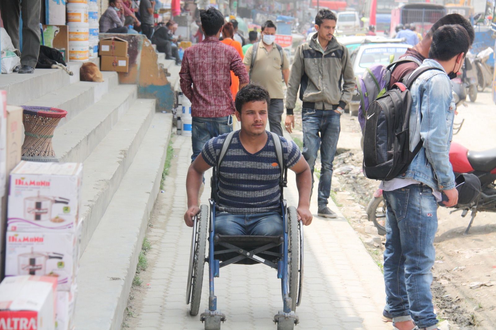 Ramesh, een jonge man die zijn beide benen verloor, duwt zijn rolstoel vooruit in een straat.