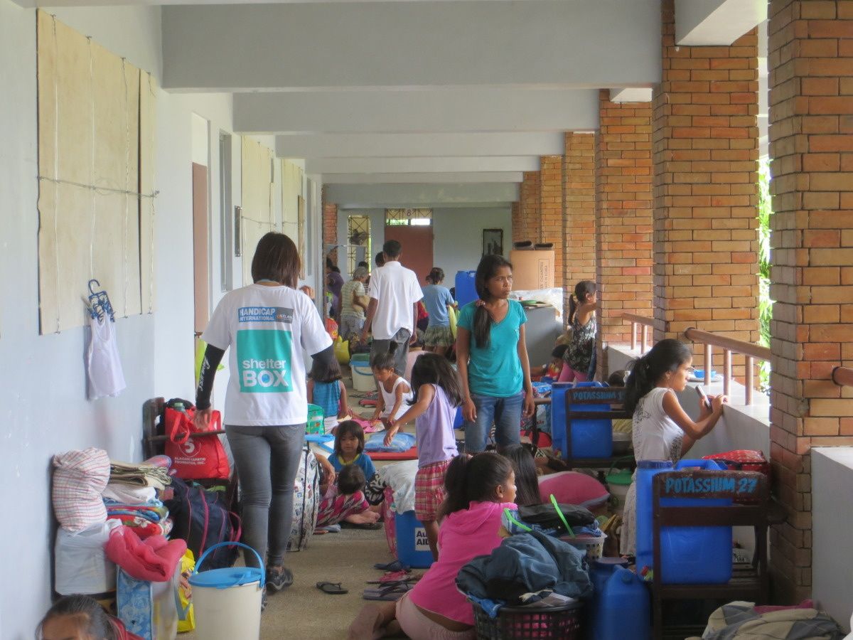 Filipino's bevinden zich in een stevig ogende gang. Een medewerker van Handicap International loopt in het midden.