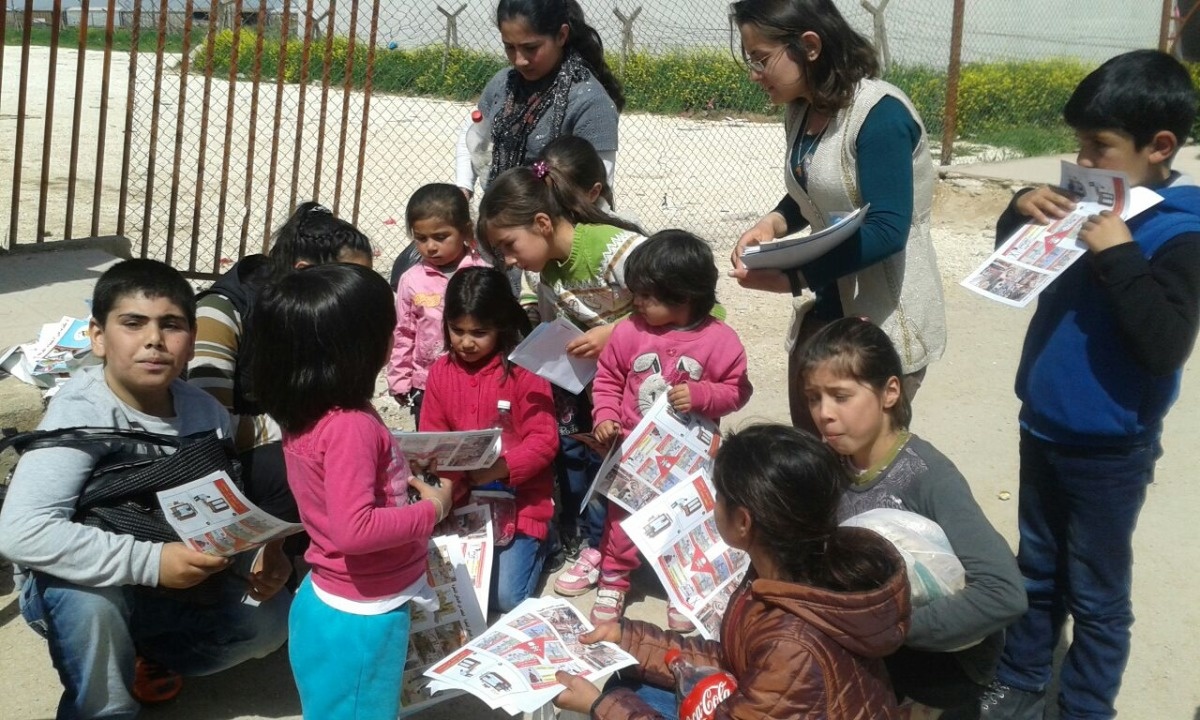 een groep kleine kinderen bekijkt de sensibiliseringsbrochures met tekeningen